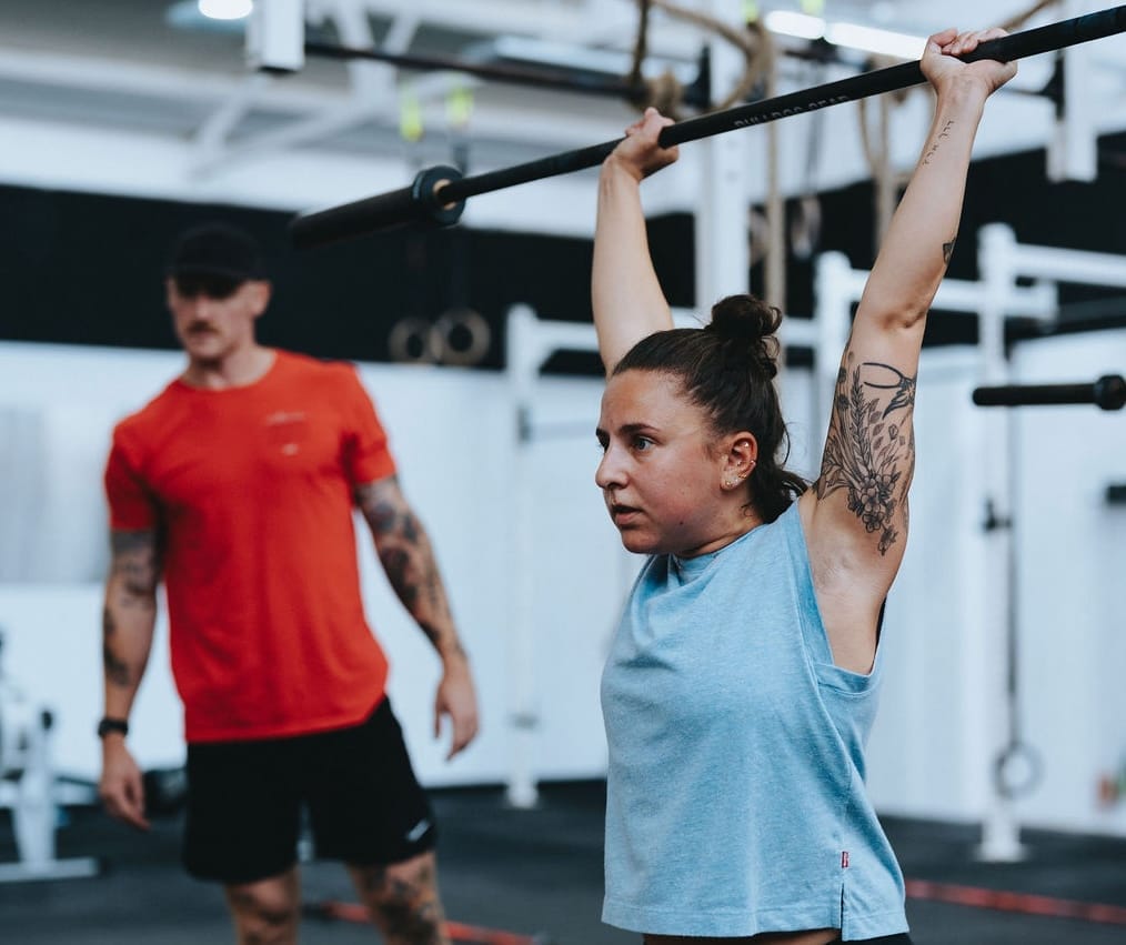 woman in personal training session with barbell overhead