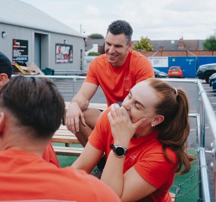 coaches laughing outside the gym on picnic table